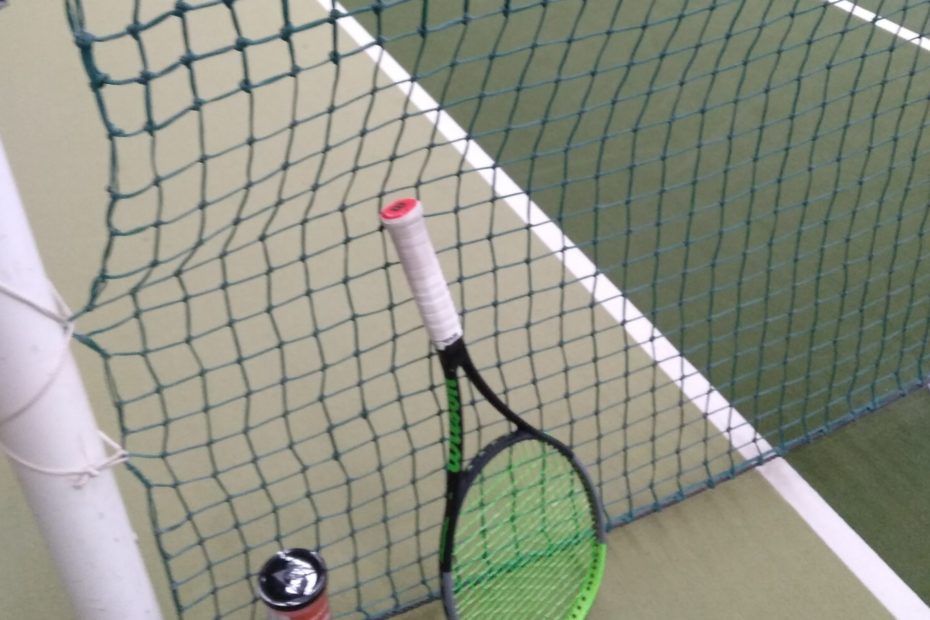 Tennisschläger und Bälle am Netzpfosten