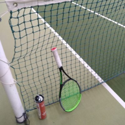 Tennisschläger und Bälle am Netzpfosten