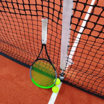 Tennisschläger und -Bälle am Netz