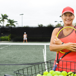 Tennis Trainerin mit Ballkorb im Training
